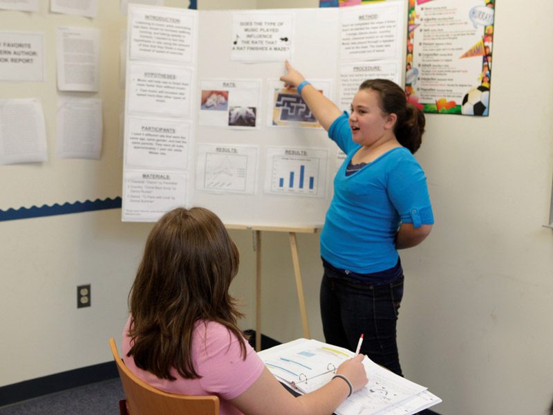 Girl pointing at a school board.