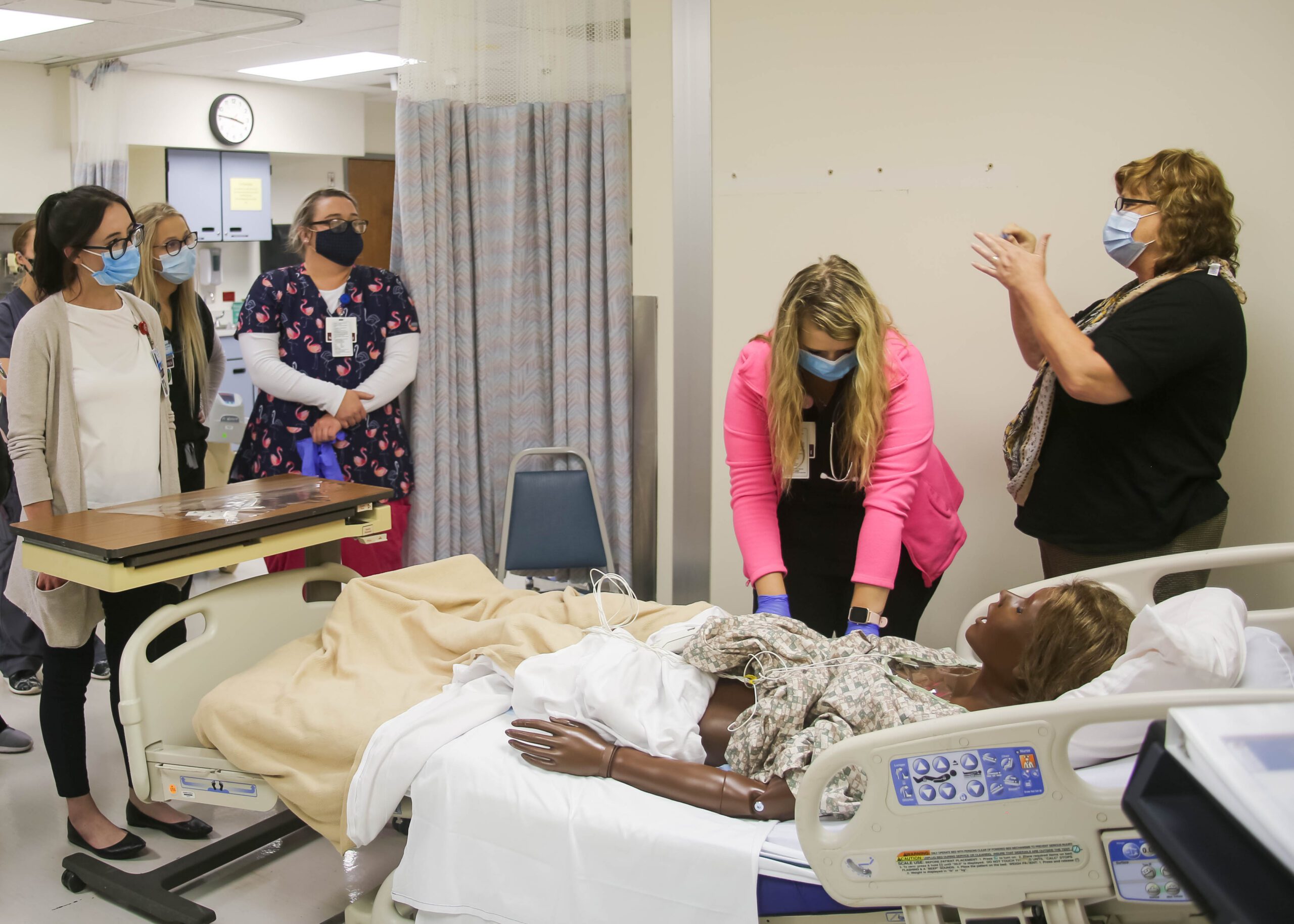 Nursers looking at a bed with a dummy in it